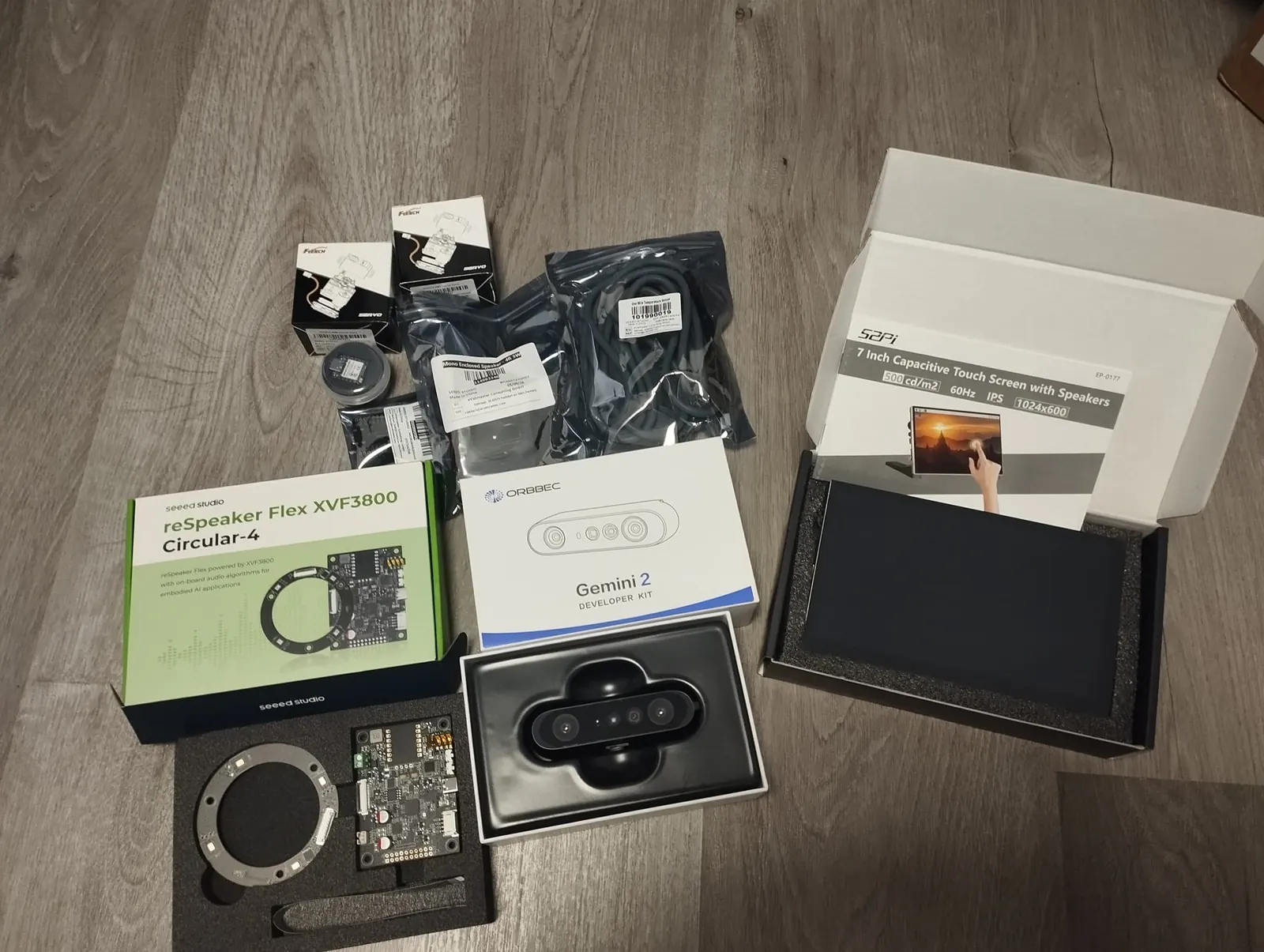 Delivered Seeed Studio components, including reSpeaker Flex, Orbbec Gemini 2, servos and a display, laid out before integration